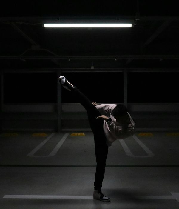 Man performing a controlled strength exercise in a dark, focused environment.
